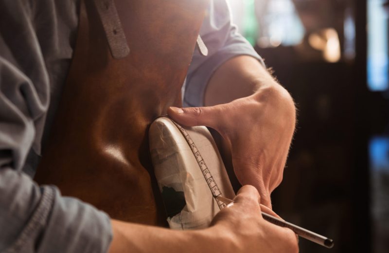 Cobbler doing measurments on a shoe with tape at his workshop